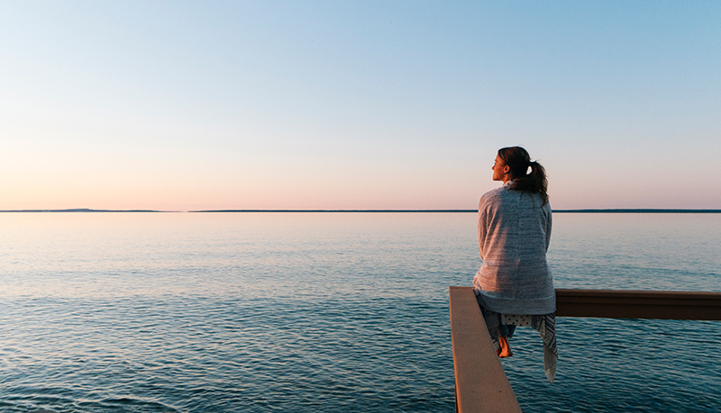 Woman looking pensive out over the ocean | Alliant Private Client